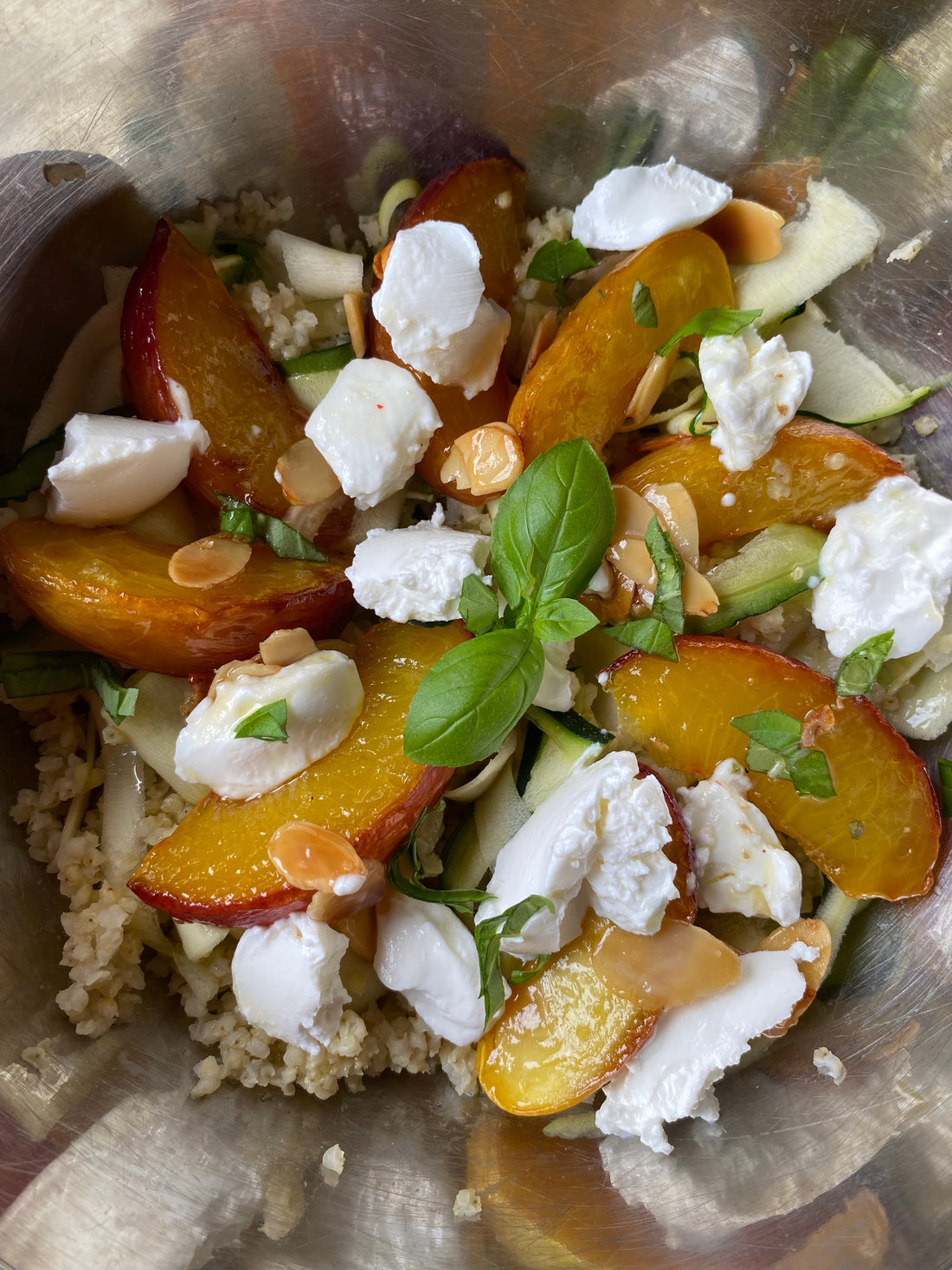 Salade de millet garnie de pêches rôties, de fines lamelles de courgette, de chèvre frais, d’amandes et de basilic.