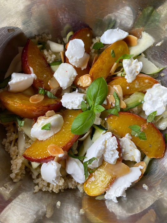 Salade de millet garnie de pêches rôties, de fines lamelles de courgette, de chèvre frais, d’amandes et de basilic.